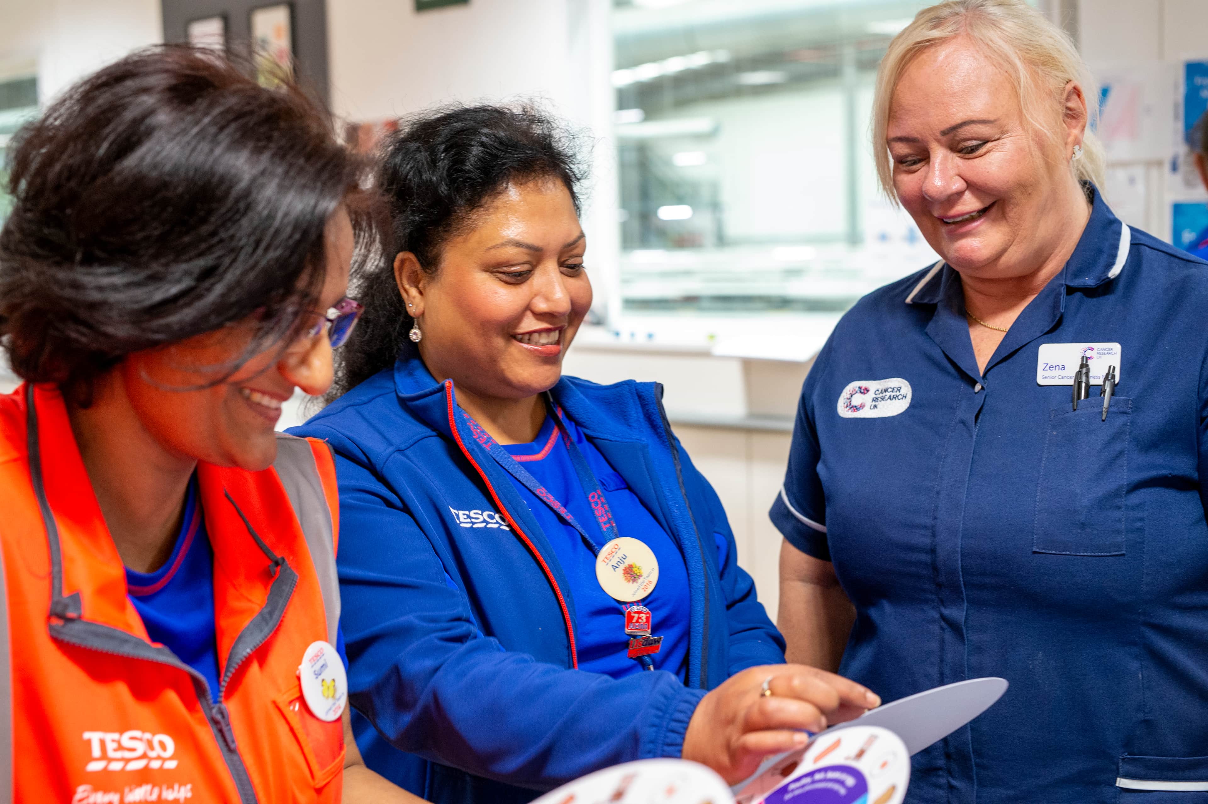 Two Tesco employees and a Cancer Research UK nurse discuss cancer awareness.