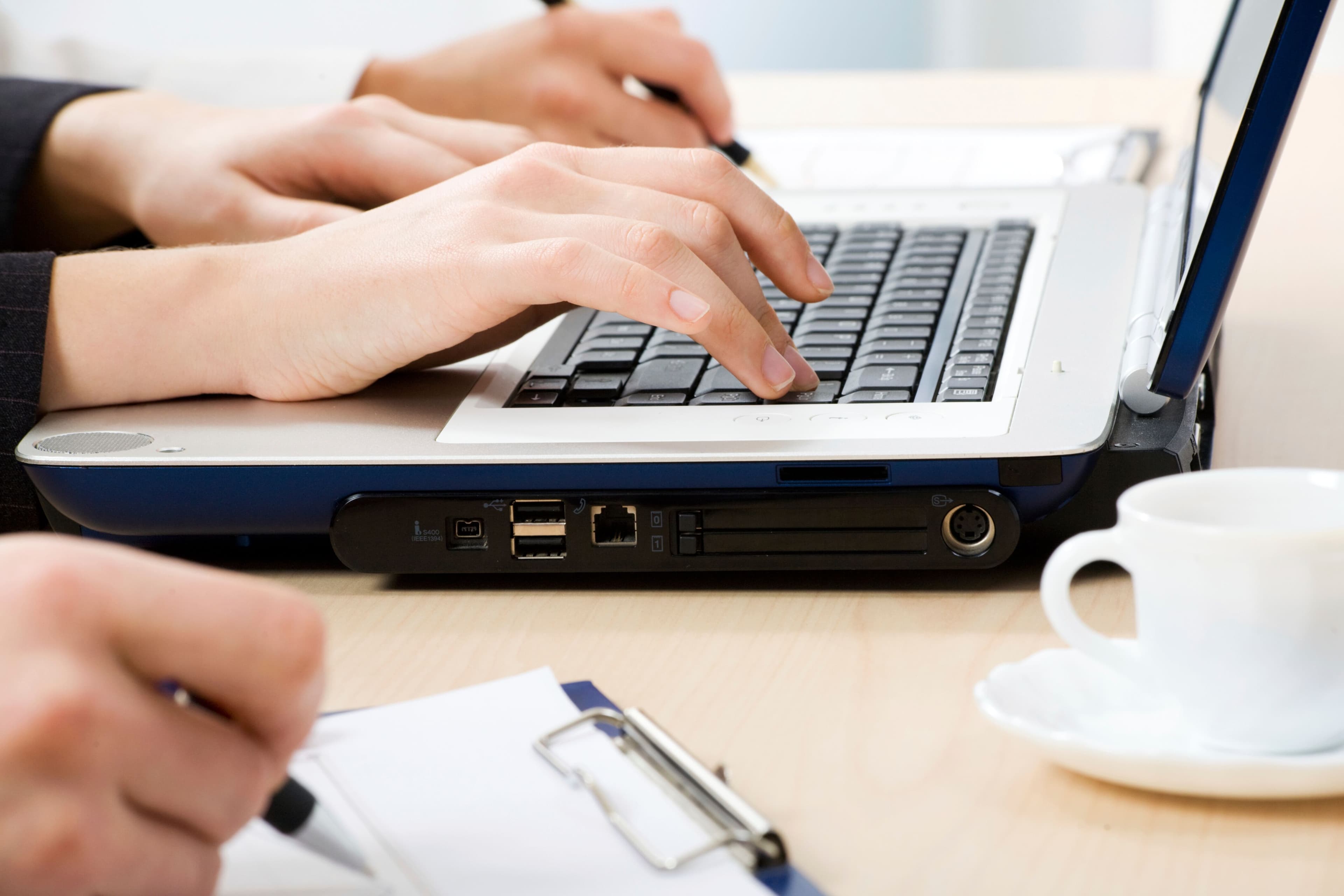 Photo of person's hands typing on a laptop.