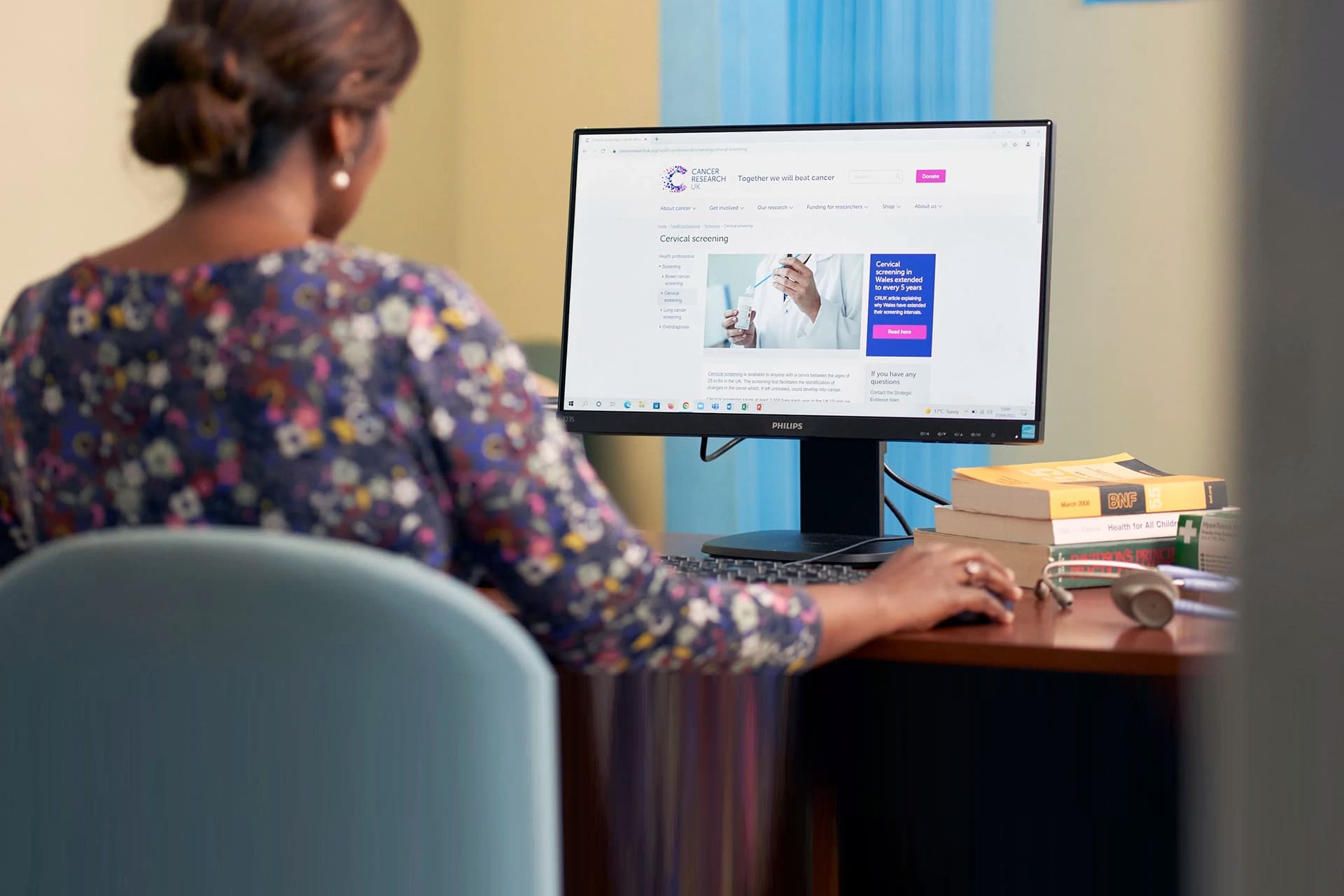 Photo of a woman looking at the Cancer Research UK website on her computer.